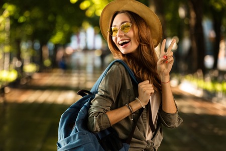 Image of excited beautiful young happy woman walking outdoors with backpack.