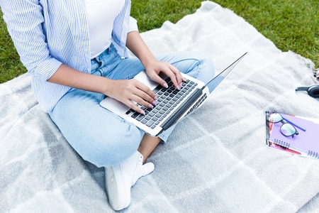 Cropped photo of young woman in park outdoors using laptop computer.の写真素材