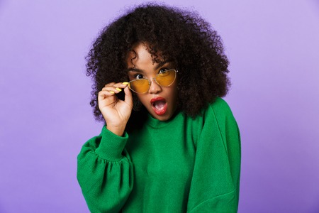 Picture of shocked pretty african woman isolated over violet background wearing glasses.の写真素材