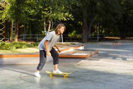 Joyful young guy spending time at the skate park, riding on a skateboardの写真素材