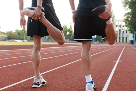Cropped photo of young two twins brothers make stretching exercises outdoors.の写真素材