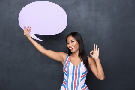Image of beautiful asian woman 30s holding blank thought bubble above her head with copyspace for...