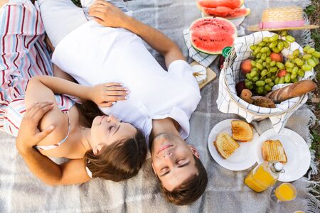 Top view of a lovely young couple laying on a blanket, having picnic