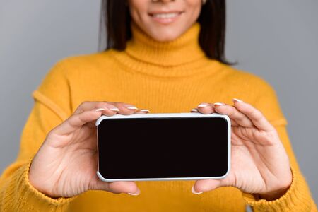 Cropped image of amazing excited woman posing isolated over grey wall background showing display of...