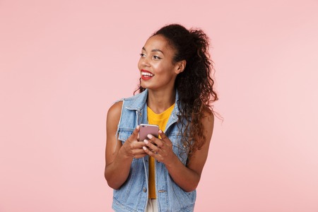 Image of pretty young happy beautiful woman posing isolated over pink background chatting by phone.