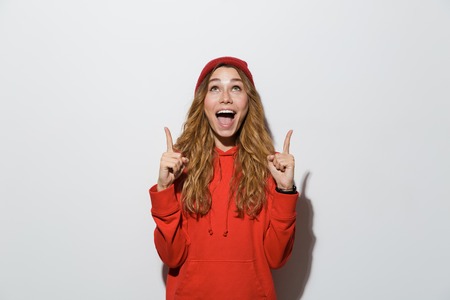 Image of happy excited young woman posing isolated over grey wall background pointing.の写真素材