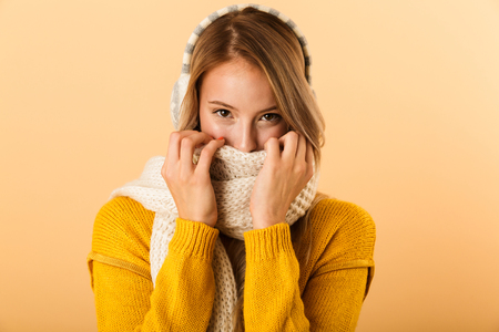 Photo of a happy woman wearing scarf isolated over yellow wall background.の写真素材
