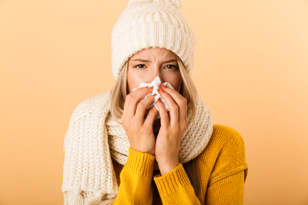 Photo of sad ill woman in plaid isolated over yellow wall background holding napkin.の写真素材