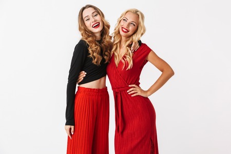 Image of a happy young two girls friends posing isolated over white wall dressed in black and red clothes.の写真素材