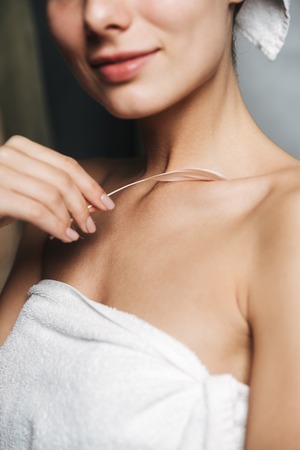 Close up pof pretty young woman wrapped in towel holding a feather indoorsの写真素材
