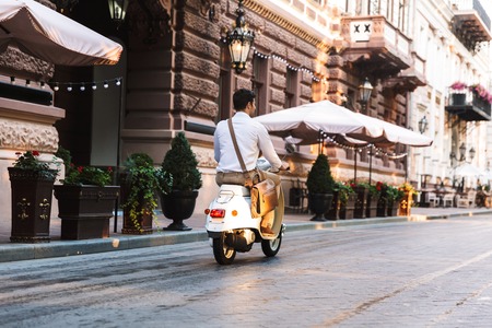 Back view of a young businessman riding on a motorbike outdoors on a city streetの写真素材