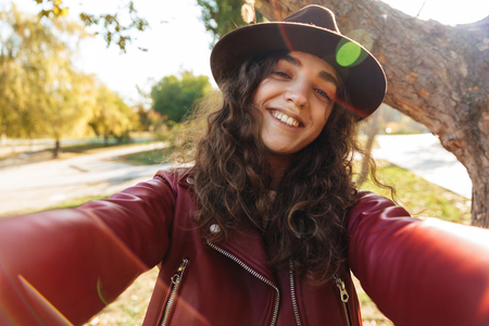 Image of a beautiful cute woman sitting in park take a selfie by camera.の写真素材