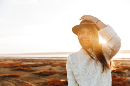 Beautiful young woman walking outdoors at the beach during sunsetの写真素材