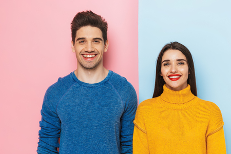 Cheerful young couple standing isolated over two colored backgroundの写真素材