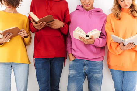 Close up of a group of cheerful smiling teenagers isolated over white background, reading books, studyingの写真素材