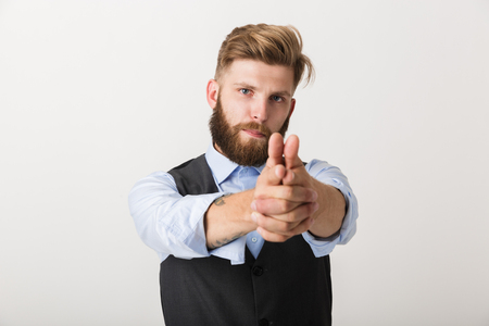 Confident young business man standing isolated over white background, pointing at copy spaceの写真素材