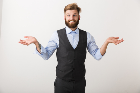 Confused young business man standing isolated over white background, shrugging shouldersの写真素材