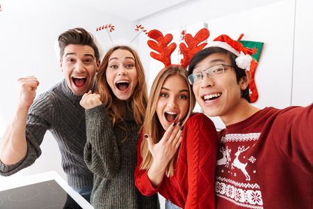 Group of excited multiethnic people celebrating New Year and taking selfie photo togetherの写真素材