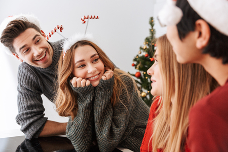 Group of funny multiethnic people men and women laughing while celebrating New Year at homeの写真素材