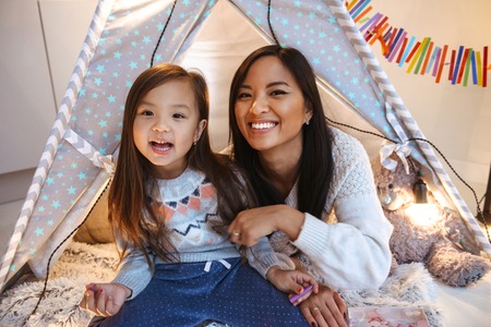 Photo of a happy young asian woman with her little daughter having fun on floor. Christmas concept.の写真素材