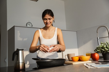 Image of a pretty healthy woman in the kitchen standing daily morning routine cooking breakfast.の写真素材