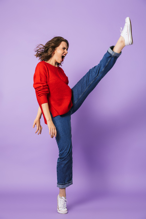 Image of an excited beautiful young woman posing isolated over purple background wall.の写真素材