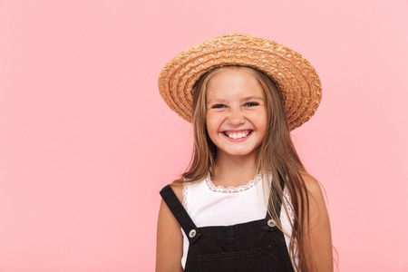 Portrait of a cheerful little girl wearing summer hat isolated over pink background