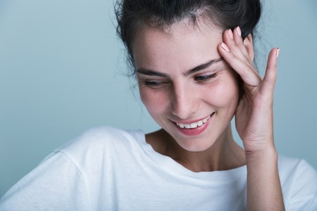 Close up of a casual beautiful young girl isolated over blue background, looking away