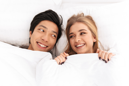 Happy young couple laying in bedの写真素材