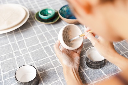 Close up of a woman making ceramic and pottery tableware at the workshop, working with clayの写真素材