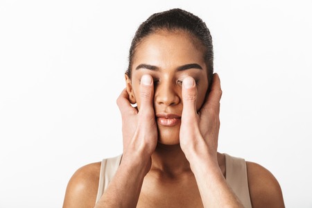 Image of african woman posing isolated over white wall background while someone's hands covering her eyes.の写真素材