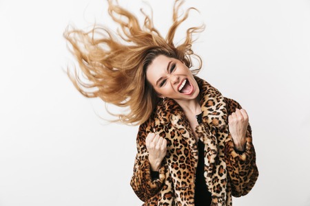 Beautiful young woman wearing leopard coat standing isolated over white background, posingの写真素材