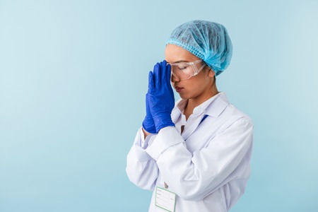 Photo of a young woman doctor posing isolated over blue wall background.の写真素材