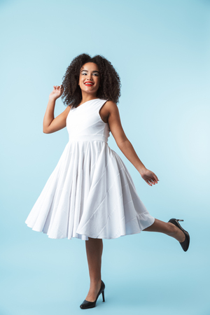 Full length of a happy african woman wearing dress celebrating isolated, posingの写真素材