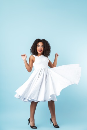 Full length of a happy african woman wearing dress celebrating isolated, posingの写真素材