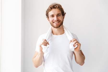 Photo of a handsome happy young man in bathroom at home cleaning brushing his teeth.の写真素材