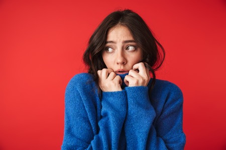 Photo of a beautiful shocked young woman posing isolated over red wall background.の写真素材