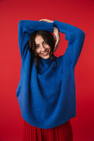 Photo of a beautiful young woman posing isolated over red wall background.の写真素材