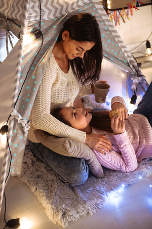 Image of a happy young woman with her little daughter girl hugging on floor holding cocoa drinking. Christmas concept.の写真素材