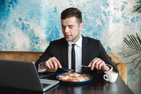 Image of a handsome young businessman sitting in cafe using laptop computer have a breakfast or dinner eat.の写真素材