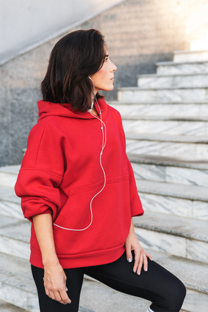 Beautiful young sports woman doing stretching exercises outdoors, wearing earphonesの写真素材