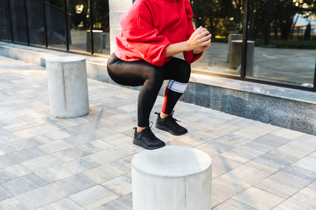 Confident fit sportswoman doing exercises outdoorsの写真素材