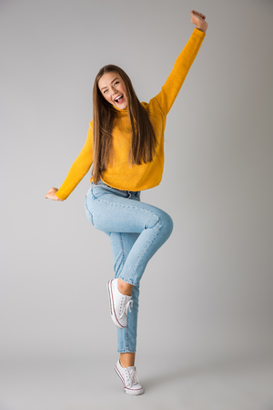 Photo of a beautiful excited young happy woman isolated over grey wall background.の写真素材