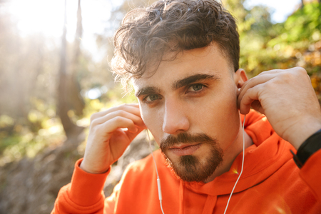 Picture of handsome young sports fitness man runner outdoors in park listening music with earphones.の写真素材