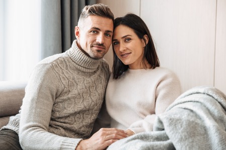 Image of a loving couple family sitting on sofa indoors on sofa.の写真素材