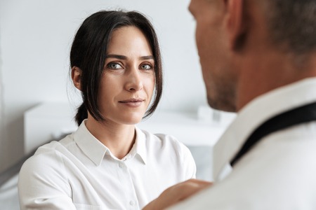 Image of a young woman help to her husband boyfriend with tie formal clothes indoors at home.の写真素材