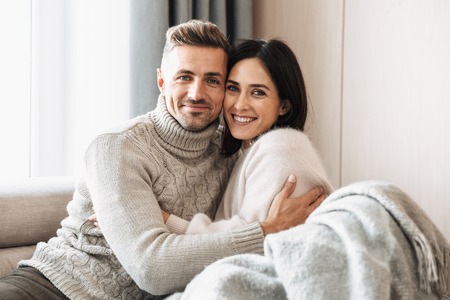 Image of a loving couple family sitting on sofa indoors on sofa.