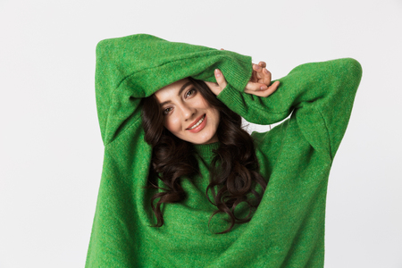 Image of beautiful young woman dressed in green sweater posing isolated over white wall background.の写真素材