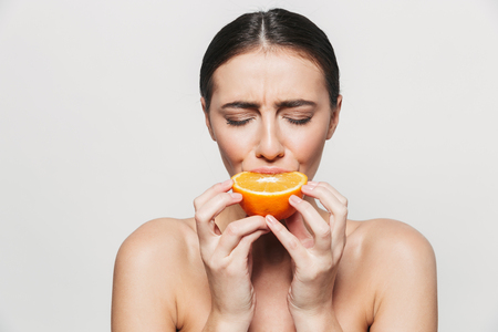 Beauty portrait of a young healthy attractive brunette woman standing isolated over white background, posing with sliced lemon and orangeの写真素材