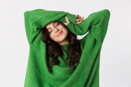 Image of beautiful young woman dressed in green sweater posing isolated over white wall background.の写真素材